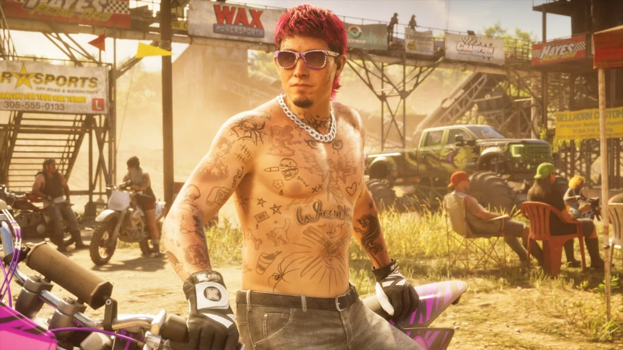 GTA 6 screenshot from Edge — a shirtless, heavily tattooed man with pink hair on a dirt bike at an off-road event, trucks and spectators behind him