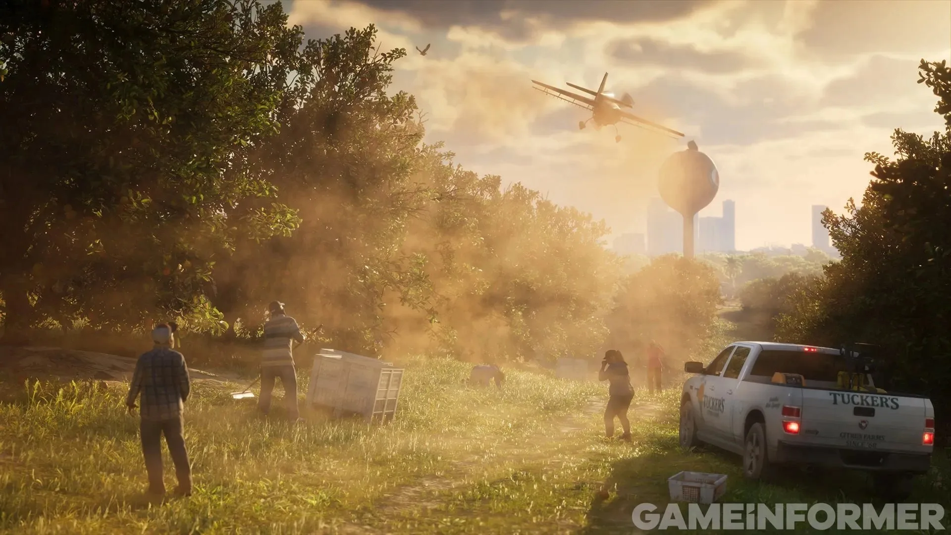 GTA 6 screenshot from Game Informer — a crop duster over a citrus grove, pickers and a farm pickup, a water tower on the horizon