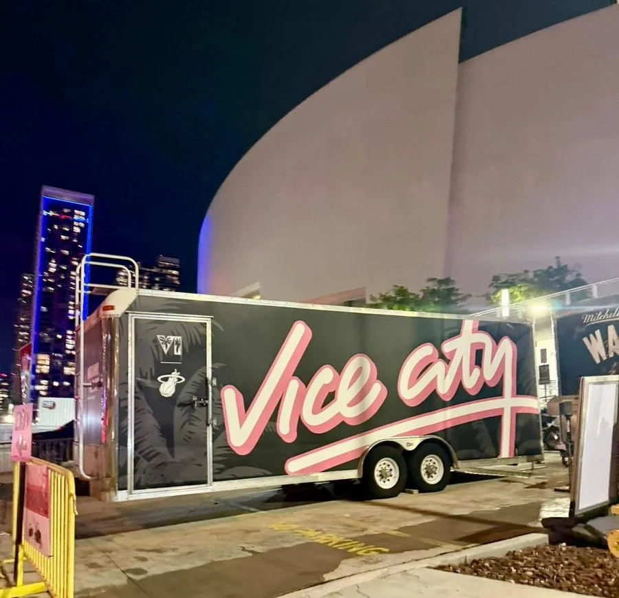Black cargo trailer with Vice City lettering and Miami Heat and VI logos parked outside the Kaseya Center in Miami at night