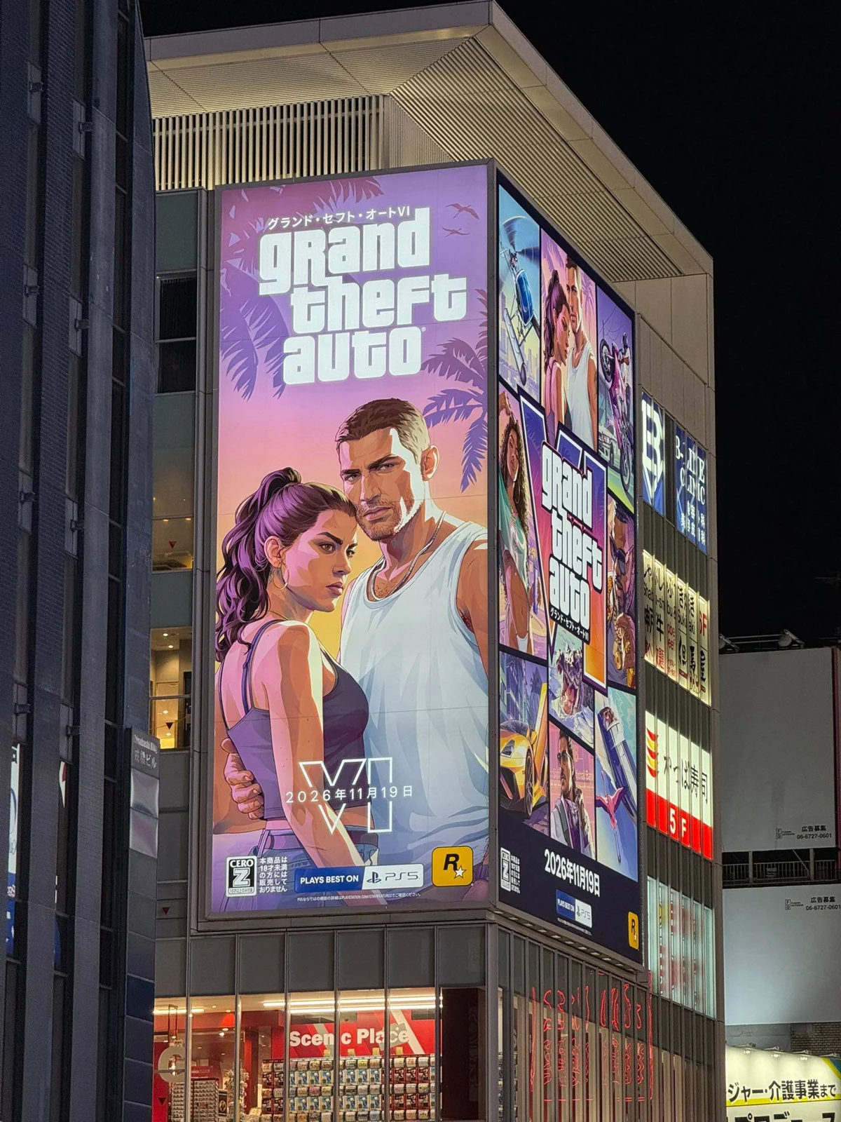 GTA 6 billboard in Osaka at night: Jason and Lucia cover art with the logo and the katakana name, the art collage on the side of the building